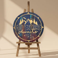 Decorative wooden sign with 'Adventure Awaits' text with scenic background shown in sunset colors
