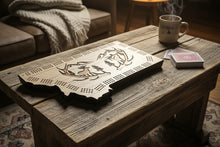 A cribbage board with a carved scene of mountain elk and deer antlers, in the shape of Montana. Montana Made